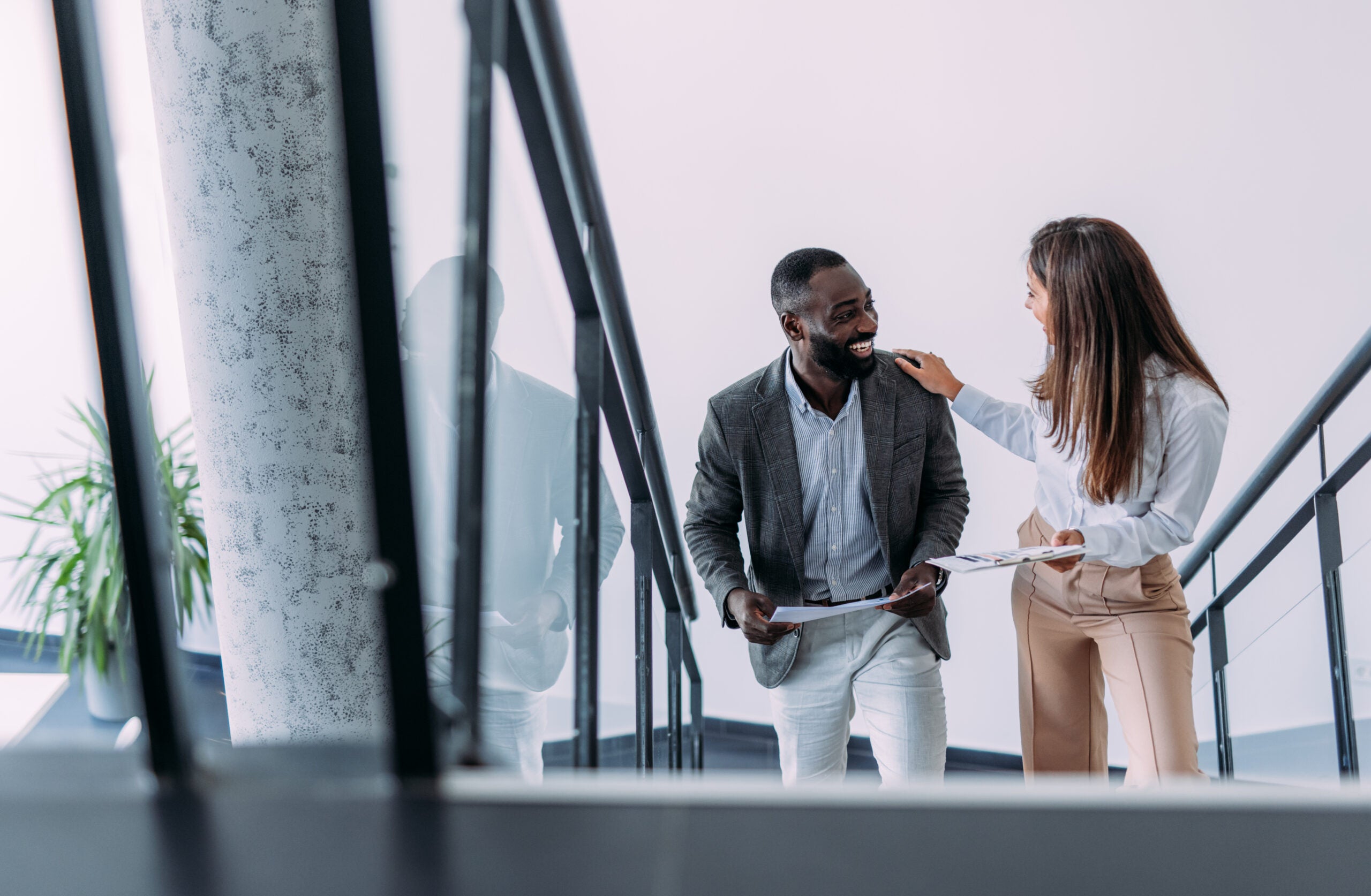 Shot of two colleagues discussing business strategy while walking up the stairs in a modern office. Two business people in a motion on stairs in the office.