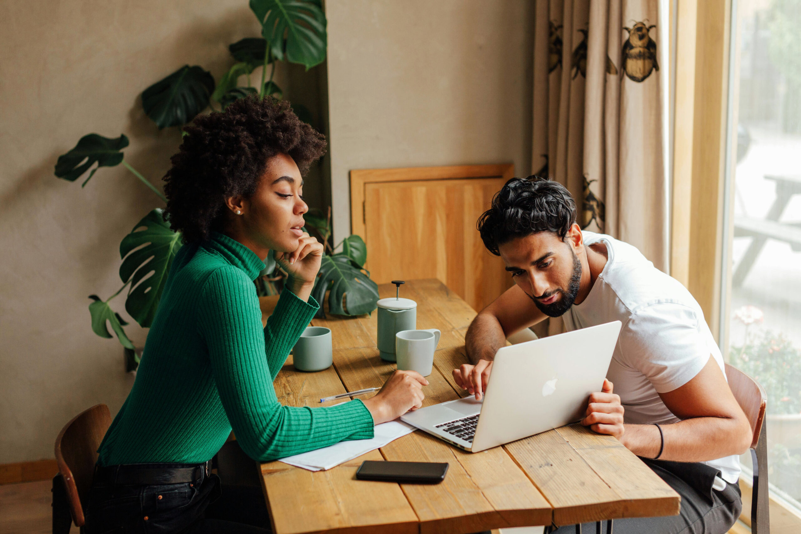 two people sitting at a table looking at laptop